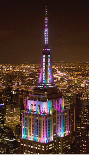 The Empire State Building at night awash in multiple pastel colors
