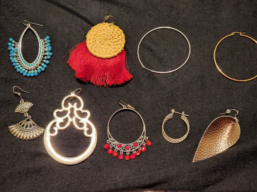 An array of earrings without matches spread out on a black cloth